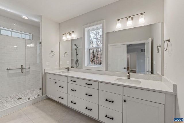 full bath with double vanity, a shower stall, tile patterned floors, and a sink