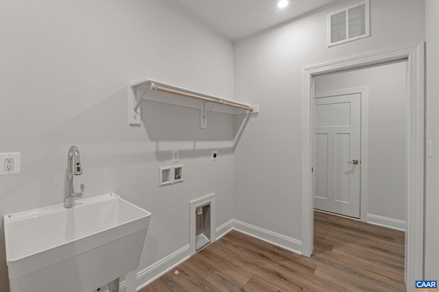 washroom featuring visible vents, a sink, wood finished floors, hookup for a washing machine, and laundry area