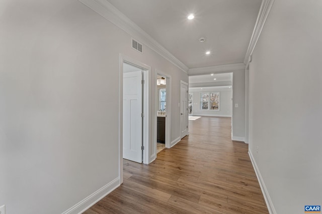 hall with visible vents, wood finished floors, recessed lighting, crown molding, and baseboards