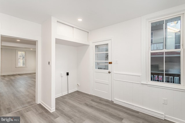 clothes washing area featuring recessed lighting, a baseboard radiator, a wainscoted wall, and wood finished floors