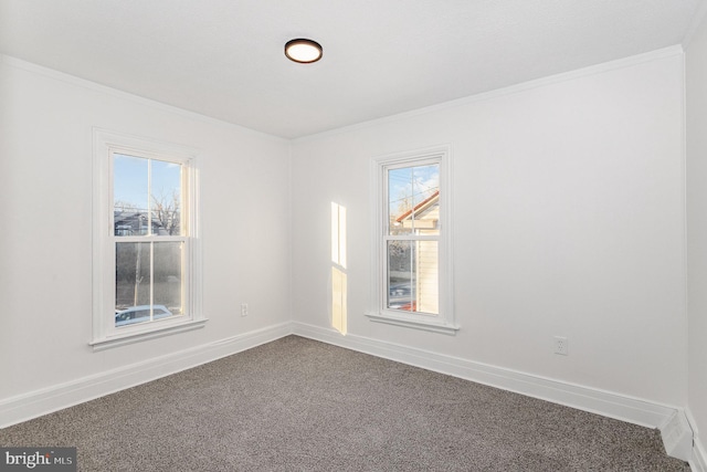 empty room with dark carpet, baseboards, crown molding, and a healthy amount of sunlight