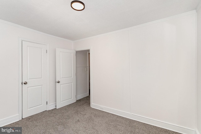 unfurnished bedroom featuring a textured ceiling, carpet, and ornamental molding