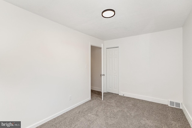 carpeted spare room featuring visible vents and baseboards