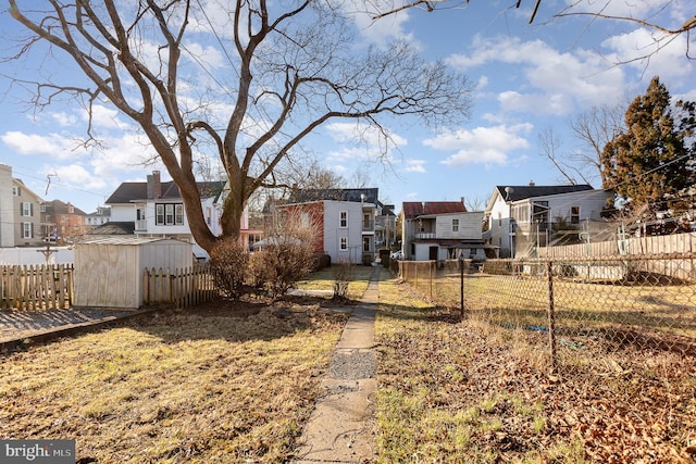 view of yard with a storage unit, a residential view, an outbuilding, and fence