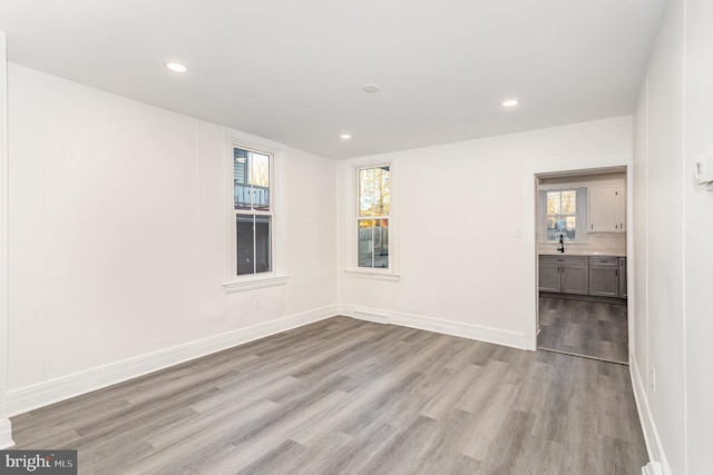 empty room with recessed lighting, baseboards, plenty of natural light, and light wood-style floors