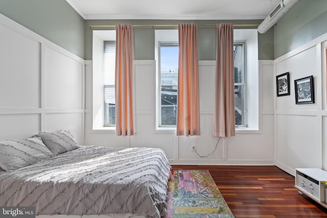 bedroom featuring dark wood-type flooring, a decorative wall, and ornamental molding