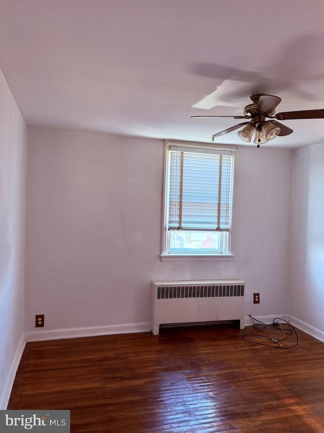 spare room with ceiling fan, radiator heating unit, baseboards, and wood finished floors