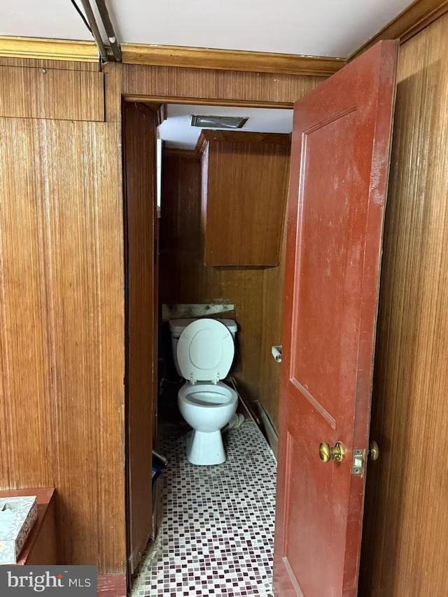 bathroom featuring tile patterned floors, toilet, and wooden walls