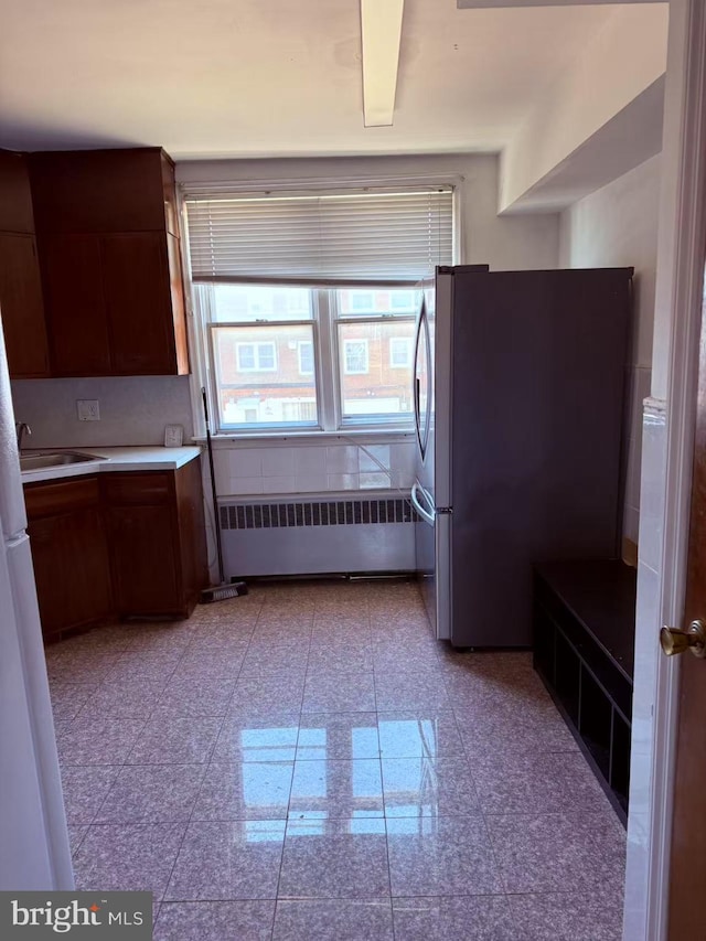 kitchen with granite finish floor, radiator, light countertops, and freestanding refrigerator