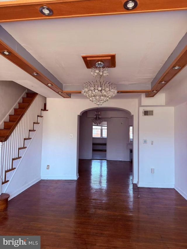 interior space featuring wood finished floors, visible vents, baseboards, arched walkways, and stairs