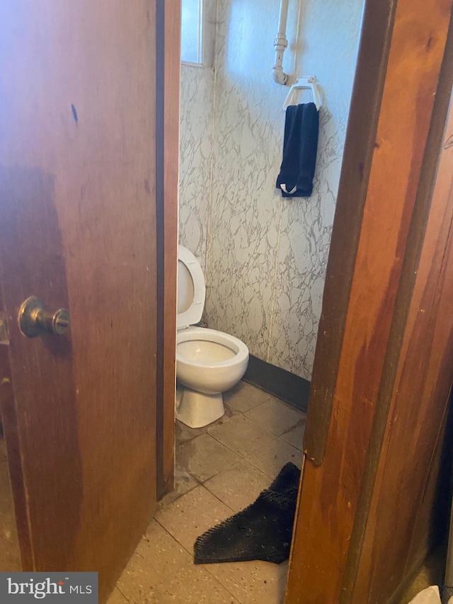 bathroom featuring tile patterned flooring, toilet, wallpapered walls, and baseboards