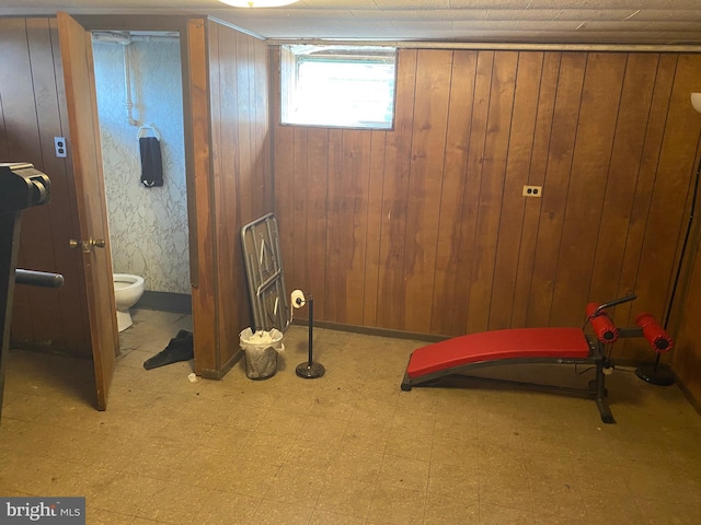 basement featuring tile patterned floors, baseboards, and wood walls