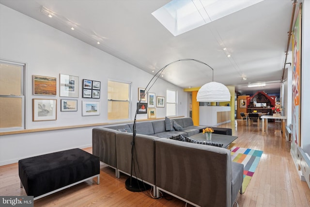 living room featuring vaulted ceiling with skylight and wood-type flooring