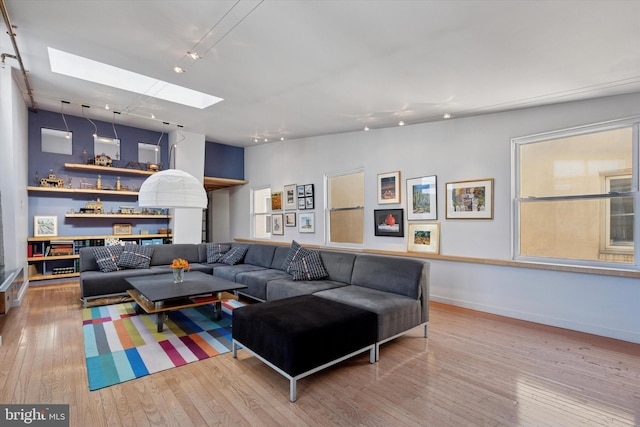 living area featuring hardwood / wood-style flooring, baseboards, and lofted ceiling with skylight