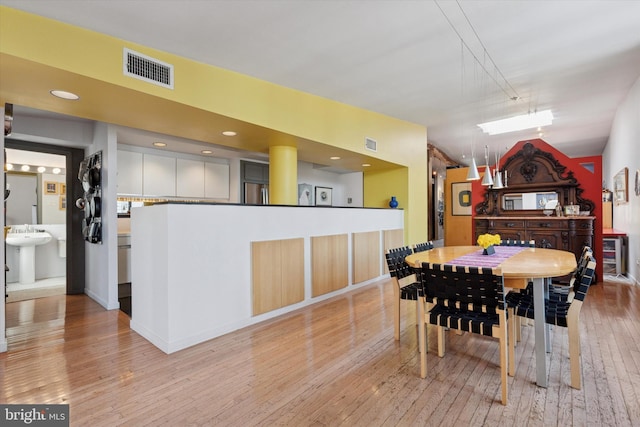 dining room with visible vents, lofted ceiling, and light wood finished floors