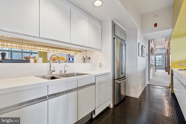 kitchen with a sink, stainless steel fridge, dishwasher, and light countertops