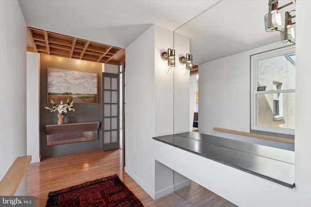 hall featuring wood finished floors, baseboards, and coffered ceiling