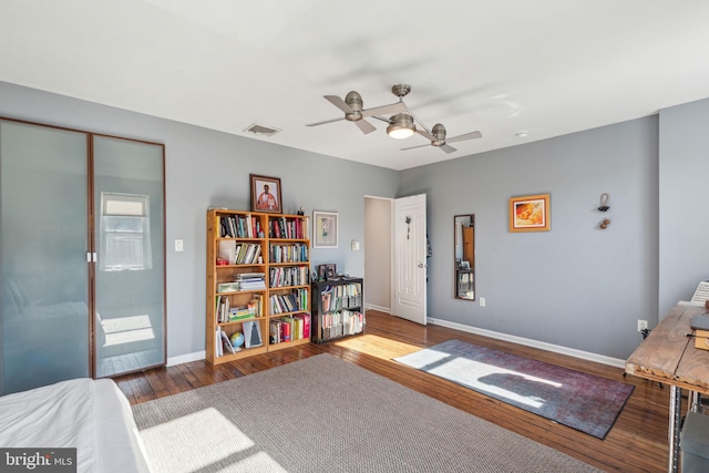 bedroom featuring visible vents, a ceiling fan, baseboards, and hardwood / wood-style flooring