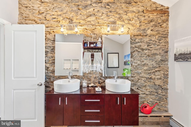 full bathroom featuring double vanity, a baseboard radiator, and a sink