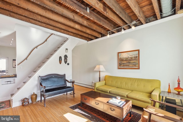 living area with stairway, beamed ceiling, a baseboard heating unit, and wood-type flooring