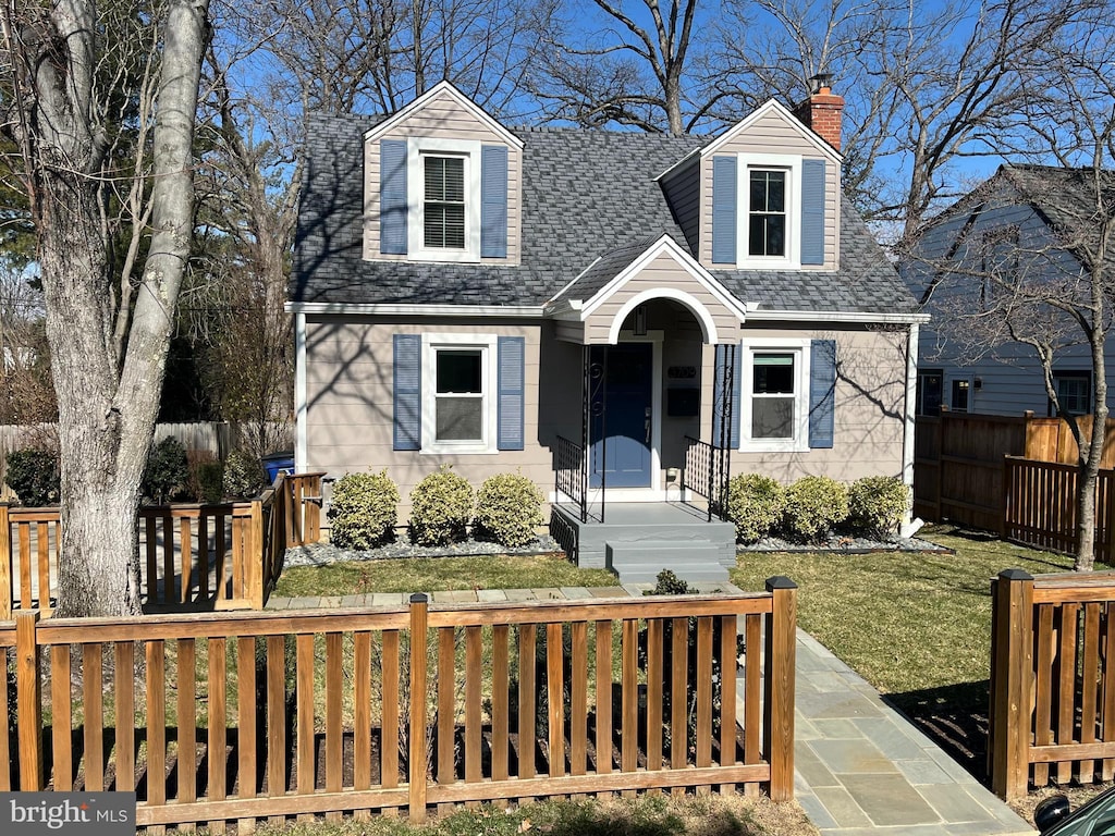 cape cod home with a fenced front yard, a chimney, a front yard, and a shingled roof