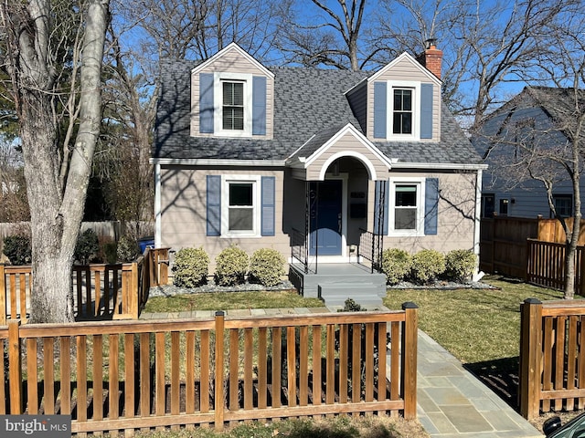 cape cod home with a fenced front yard, a chimney, a front yard, and a shingled roof