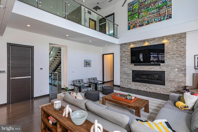 living area featuring wood finished floors, baseboards, a fireplace, stairs, and a towering ceiling