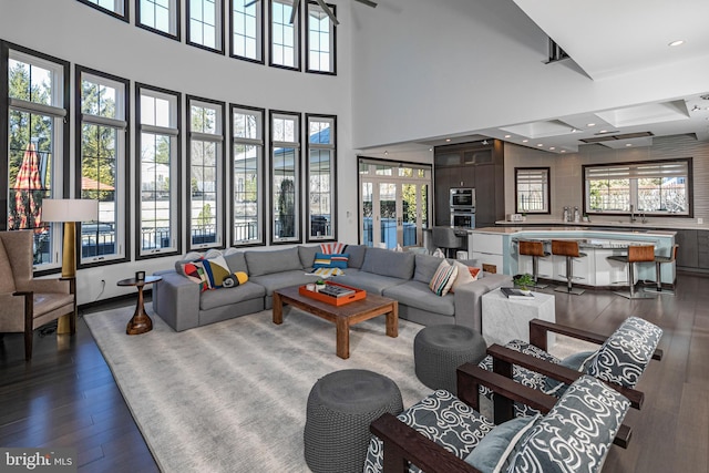 living room with recessed lighting, dark wood-style flooring, and a towering ceiling