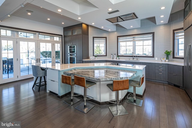 kitchen with visible vents, a kitchen bar, a large island, modern cabinets, and a sink