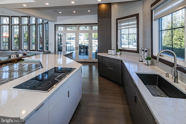 kitchen with light stone countertops, a sink, french doors, black electric cooktop, and modern cabinets