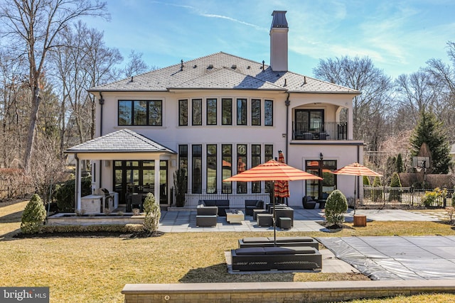 rear view of property with a balcony, fence, a yard, a patio area, and an outdoor hangout area