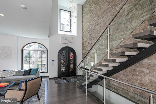 foyer entrance featuring wood finished floors, a towering ceiling, french doors, and a wealth of natural light