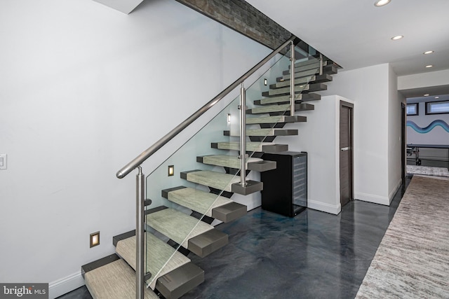 stairs with recessed lighting, baseboards, and concrete floors