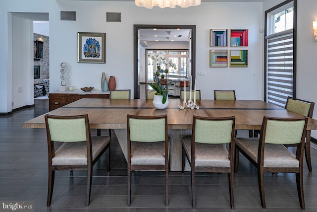 dining space featuring wood finished floors, a fireplace, and visible vents