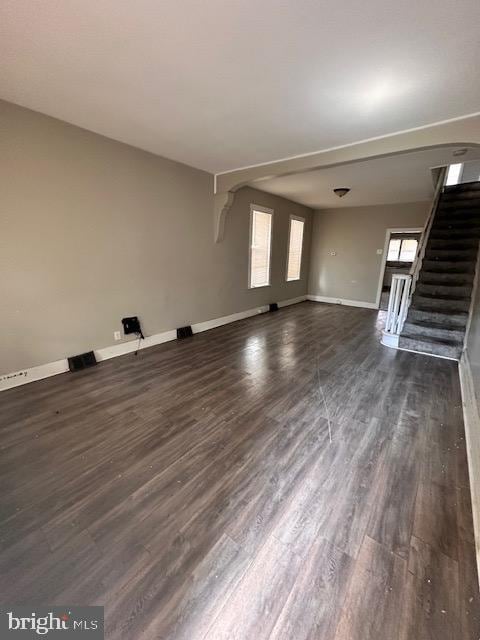 unfurnished living room featuring stairs, visible vents, dark wood finished floors, and baseboards