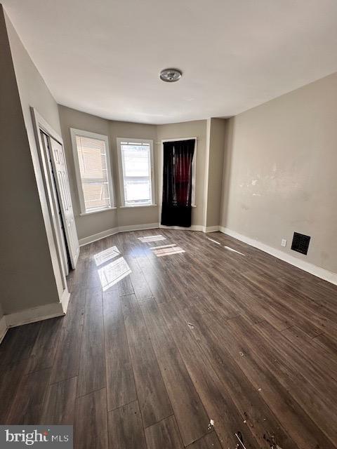 unfurnished living room with baseboards and dark wood finished floors