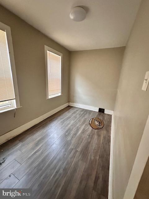 unfurnished room with a wealth of natural light, baseboards, and wood finished floors