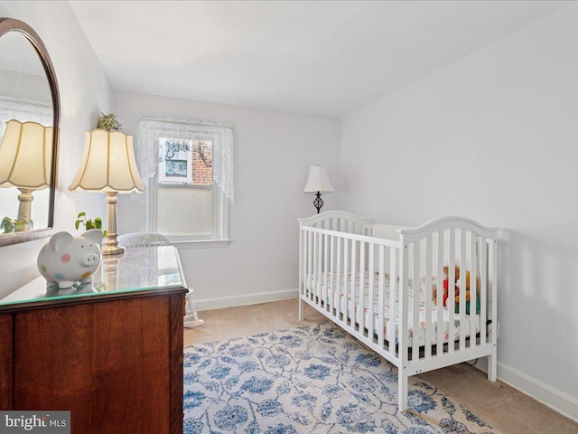 bedroom with a nursery area, baseboards, and carpet floors