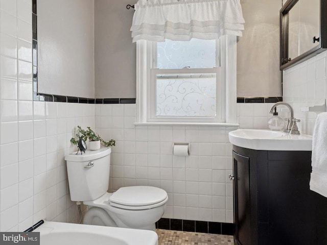 bathroom with toilet, tile walls, and vanity