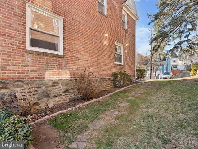 view of property exterior with a yard and brick siding