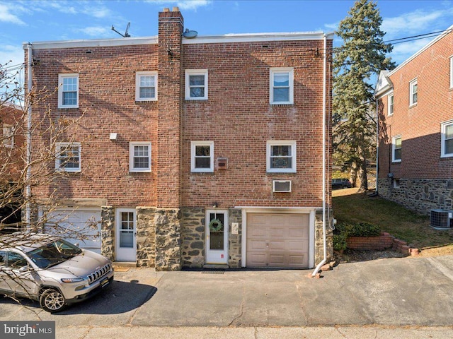 view of front of home with driveway, stone siding, brick siding, and an attached garage