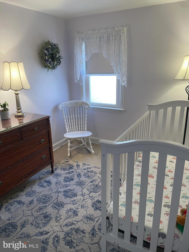 carpeted bedroom with baseboards and a nursery area