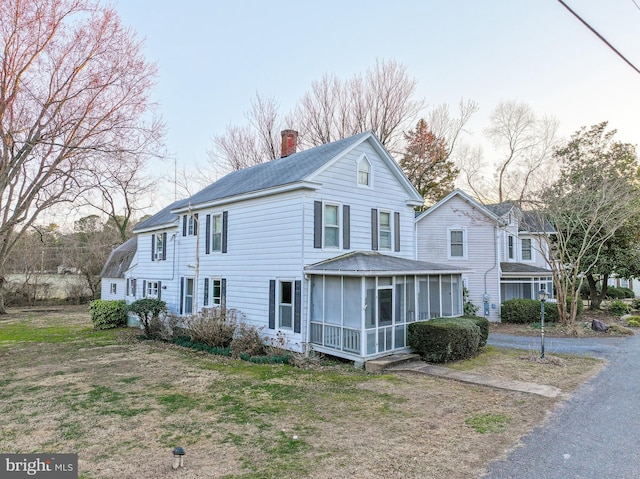 view of front of home featuring a chimney and a sunroom