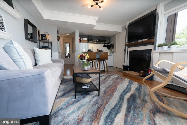 living room with a fireplace, wood finished floors, and crown molding