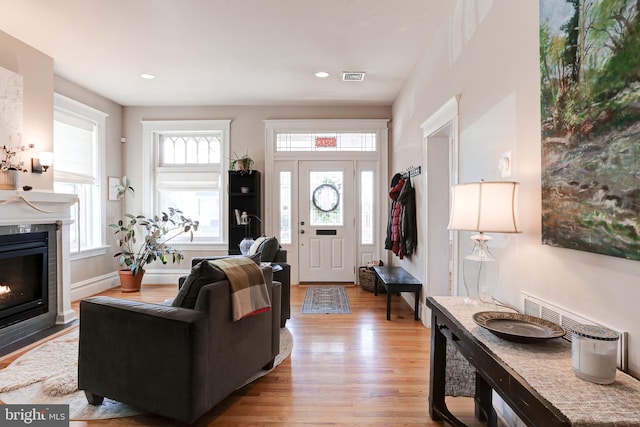 living room with light wood-style flooring, recessed lighting, baseboards, and a tile fireplace