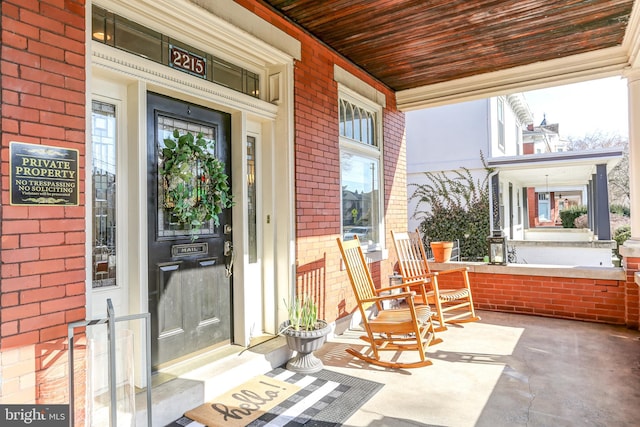 doorway to property with brick siding and a porch