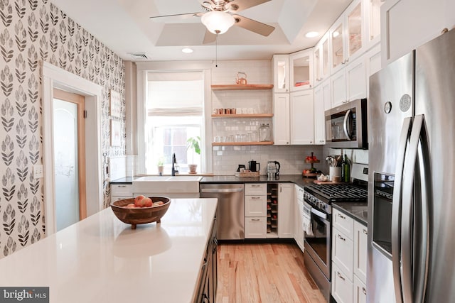 kitchen with open shelves, dark countertops, white cabinetry, stainless steel appliances, and wallpapered walls