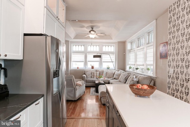 kitchen featuring ceiling fan, open floor plan, light wood-type flooring, a tray ceiling, and white cabinetry