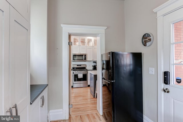 kitchen featuring decorative backsplash, appliances with stainless steel finishes, light wood-style flooring, and white cabinets