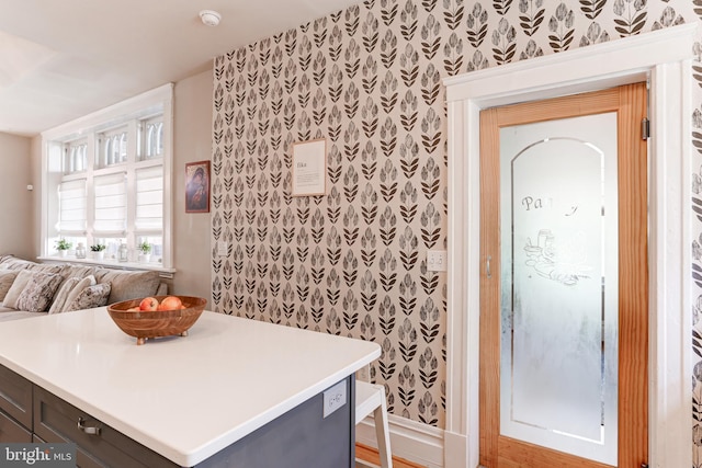 kitchen with wallpapered walls, light countertops, open floor plan, and a kitchen island